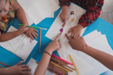 Creative kids during an art class in a daycare center or elementary school classroom drawing with female teacher.の写真素材