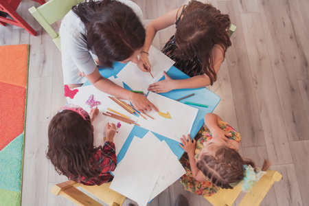 Creative kids during an art class in a daycare center or elementary school classroom drawing with...