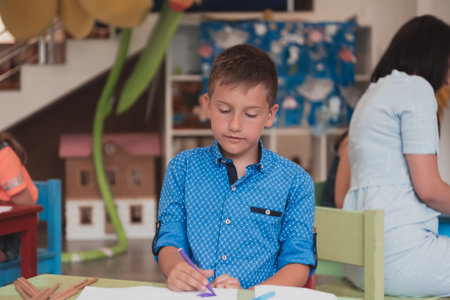 Cute girl and boy sit and draw together in preschool institutionの写真素材