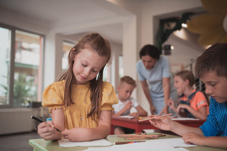 Creative kids during an art class in a daycare center or elementary school classroom drawing with...