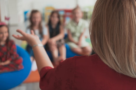 Reading time in an elementary school or kindergarten, a teacher reads a book to children in an elementary school or kindergarten. The concept of pre-school education. Selective focusの写真素材