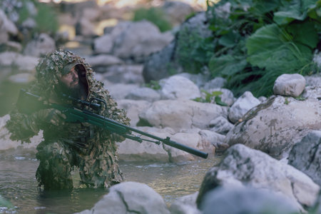 A military man or airsoft player in a camouflage suit sneaking the river and aims from a sniper...