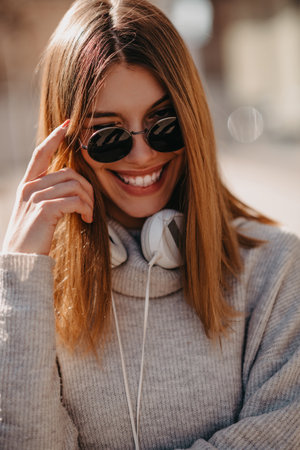 A modern girl with sunglasses walking down the street listens to music in headphones.の写真素材