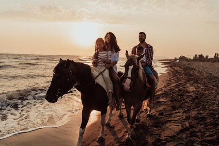 The family spends time with their children while riding horses together on a sandy beach. Selective focusの写真素材