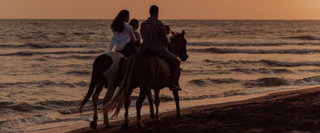 The family spends time with their children while riding horses together on a sandy beach. Selective focusの写真素材