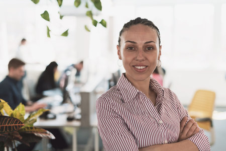 Portrait of young smiling business woman in creative open space coworking startup office. Successful businesswoman in modern office. Team of Coworkers working in background.の写真素材