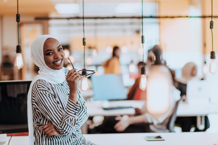 Protrait of a black ( african-american) female muslim standing in a modern business office while wearing a hijab.の写真素材