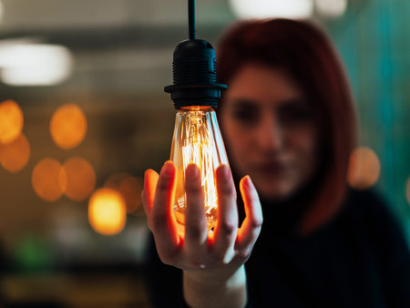 Symbolic photo of a business woman holding a light bulb in a modern officeの写真素材