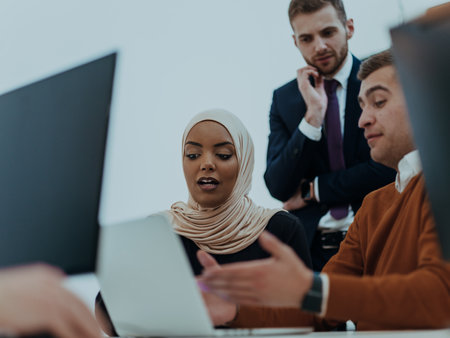 Group of multi-ethnic colleagues working on desktop computers, laptop and sharing their ideas in a modern office space.Young influencers work on online marketing projects.の写真素材