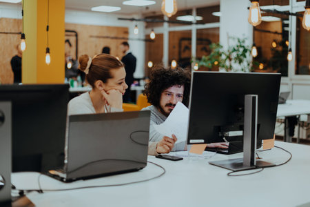 Two colleagues working on a project in modern startup offices. Guy with afro haircut and a female...