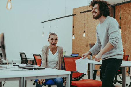 Two colleagues working on a project in modern startup offices. Guy with afro haircut and a female blonde employee working at the office.の写真素材