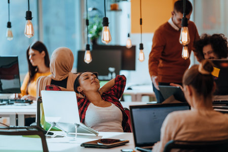 Group of multi-ethnic colleagues working on desktop computers, laptop and sharing their ideas in a modern office space.Young influencers work on online marketing projects.の写真素材