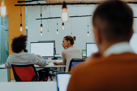 Two colleagues working on a project in modern startup offices. Guy with afro haircut and a female blonde employee working at the office.の写真素材