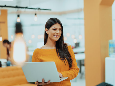 Portrait of a woman using a laptop in a modern officeの写真素材