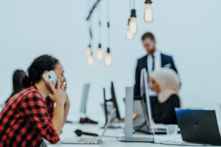 A close-up side picture of a beautiful woman looking at her smartphone while working on her laptopの写真素材
