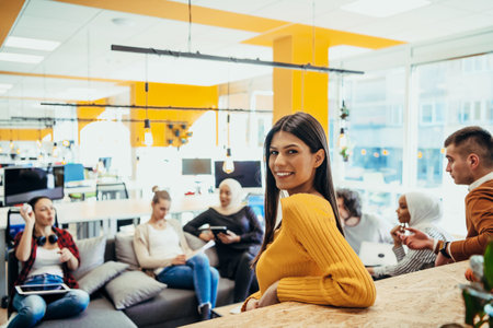 Female boss, manager executive posing in a modern startup office while being surrounded by her coworkers, team.の写真素材