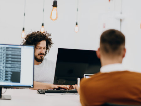 Group of multi-ethnic colleagues working on desktop computers, laptop and sharing their ideas in a...