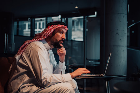 An elderly Arab man sitting in the office and analyzes data on his laptopの写真素材