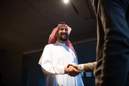 An elderly Arab man shaking hands with a businessman and ending a business meeting with successful business dealsの写真素材