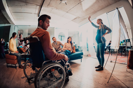 A pregnant businesswoman leads a creative meeting of a diverse business team in a modern coworking