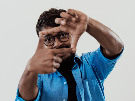 Young handsome man focusing with fingers, framing with hands isolated on grey background. Close up...