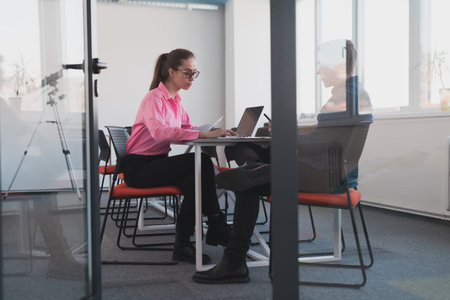 Two young entrepreneurs, a businessman and a businesswoman, sitting in a modern glass office and...