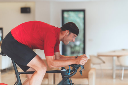 A man riding a triathlon bike on a machine simulation in a modern living room. Training during pandemic conditions.の写真素材