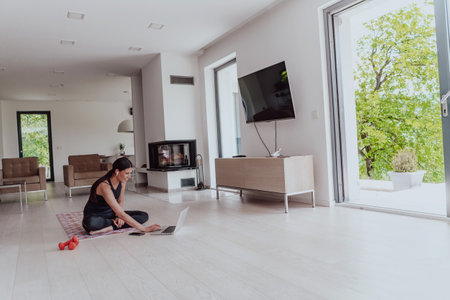 Young Beautiful Female Woman with Trainer via Video Call Conference in Bright Sunny House. Healthy Lifestyle, Wellbeing and Mindfulness Concept.の写真素材