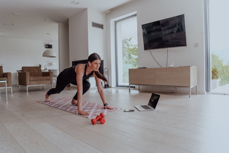 Young Beautiful Female Exercising, Stretching and Practising Yoga with Trainer via Video Call Conference in Bright Sunny House. Healthy Lifestyle, Wellbeing and Mindfulness Concept.の写真素材