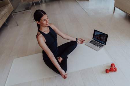 Young Beautiful Female Exercising, Stretching and Practising Yoga with Trainer via Video Call Conference in Bright Sunny House. Healthy Lifestyle, Wellbeing and Mindfulness Concept.の写真素材