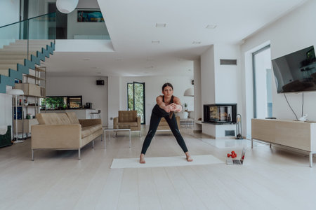 Young Beautiful Female Exercising, Stretching and Practising Yoga with Trainer via Video Call...