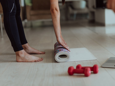 A young woman in sports clothes preparing sports equipment for online training in her living roomの写真素材