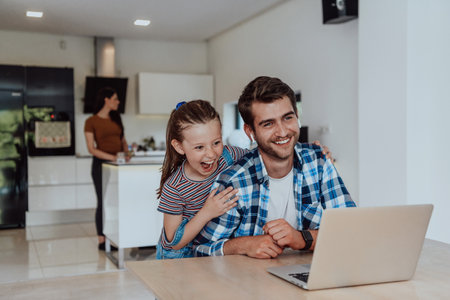 Father and daughter in modern house talking together on laptop with their family during holidays. The life of a modern familyの写真素材