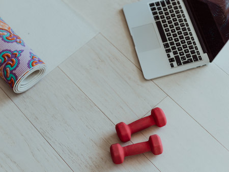 Photo of a laptop, dumbbells and headphones on the floor of the living room. Online training conceptの写真素材