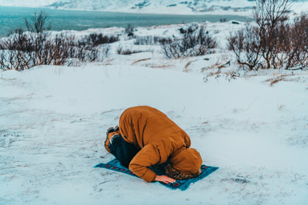 A Muslim traveling through arctic cold regions while performing the Muslim prayer namaz during breaksの写真素材