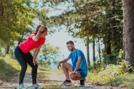 A young couple resting after an exhausting run in the early morning on an idyllic forest road