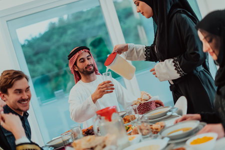 Muslim family having Iftar dinner drinking water to break feast. Eating traditional food during Ramadan feasting month at home. The Islamic Halal Eating and Drinking in modern homeの写真素材