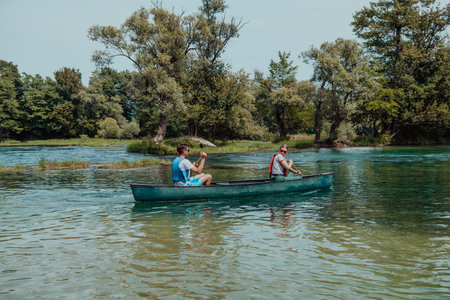 Couple adventurous explorer friends are canoeing in a wild river surrounded by the beautiful natureの写真素材