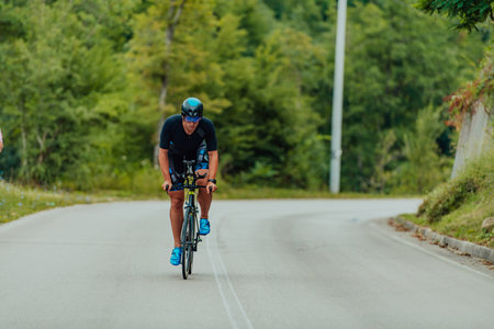Full length portrait of an active triathlete in sportswear and with a protective helmet riding a bicycle. Selective focusの写真素材