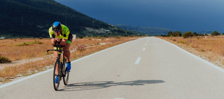 Full length portrait of an active triathlete in sportswear and with a protective helmet riding a bicycle. Selective focusの写真素材