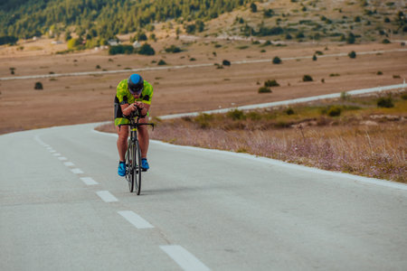 Full length portrait of an active triathlete in sportswear and with a protective helmet riding a bicycle. Selective focusの写真素材