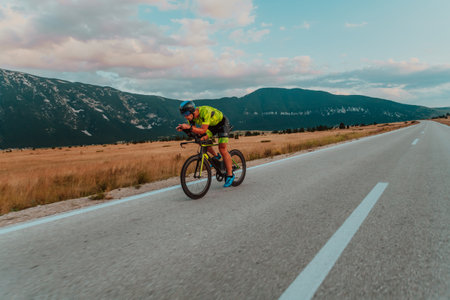 Full length portrait of an active triathlete in sportswear and with a protective helmet riding a bicycle. Selective focusの写真素材