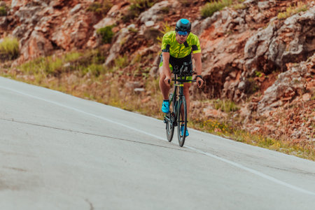 Full length portrait of an active triathlete in sportswear and with a protective helmet riding a bicycle. Selective focusの写真素材