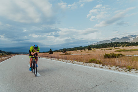 Full length portrait of an active triathlete in sportswear and with a protective helmet riding a bicycle. Selective focusの写真素材