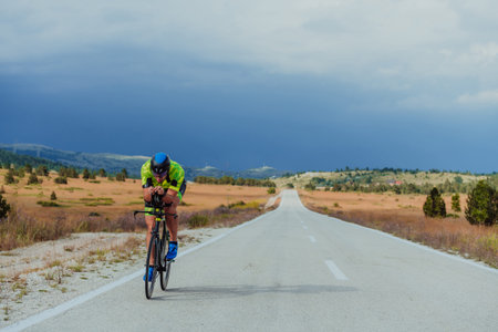 Full length portrait of an active triathlete in sportswear and with a protective helmet riding a...
