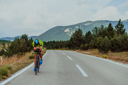 Full length portrait of an active triathlete in sportswear and with a protective helmet riding a bicycle. Selective focusの写真素材