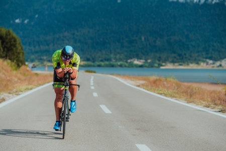 Close up photo of an active triathlete in sportswear and with a protective helmet riding a bicycle. Selective focusの写真素材
