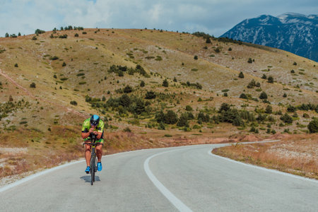 Full length portrait of an active triathlete in sportswear and with a protective helmet riding a bicycle. Selective focusの写真素材