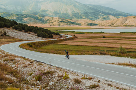 Full length portrait of an active triathlete in sportswear and with a protective helmet riding a bicycle. Selective focusの写真素材