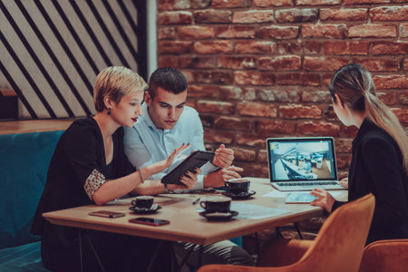 Happy businesspeople smiling cheerfully during a meeting in a coffee shop. Group of successful business professionals working as a team in a multicultural workplace.の写真素材